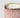 Close-up of a pink fluted mercury candle jar with metallic rose-gold speckles, a white wax fill, and a silver-toned rim on a light gray background.