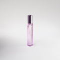 Pink perfume bottle with a metallic cap on a light gray background