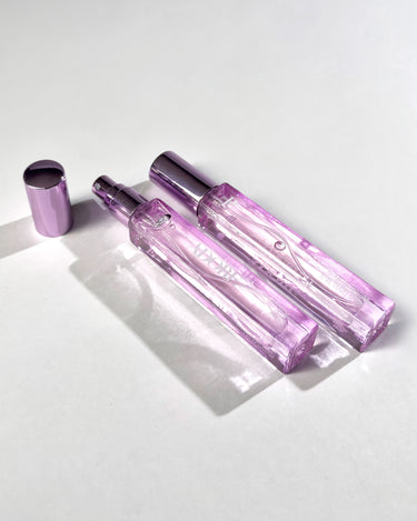 Pink perfume bottle and cap on a white surface