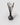 A reed diffuser with a dark smoky glass bottle, black reeds, and three dried white lotus flowers, photographed on a light gray background.