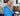 Roja Dove in a blue shirt with jewelry in a room with shelves and decor