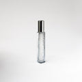Clear glass 'Leather Noir' perfume bottle with silver cap on a white background