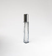 Clear glass 'Leather Noir' perfume bottle with silver cap on a white background