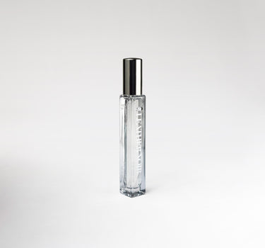Clear glass 'Leather Noir' perfume bottle with silver cap on a white background