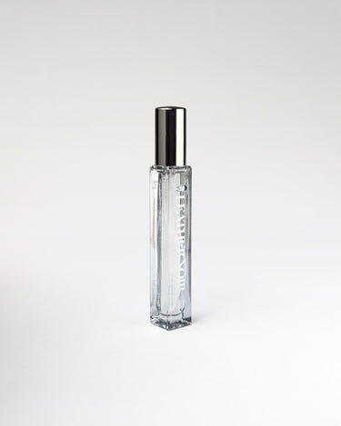 Clear glass 'Leather Noir' perfume bottle with silver cap on a white background