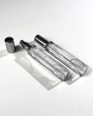 Clear glass perfume bottles with silver caps on a white background