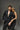 Man in a black pinstripe suit with no shirt and a woman in a black dress against a gray background