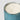 A close-up of a three-wick trackside soleil del mar candle in a ribbed mercury, vertically fluted glass container with a distressed blue finish, filled with creamy off-white natural wax, set against a plain light gray background.