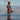 A woman in a bright blue bikini sits in shallow water at sunset, with the text 'EAU DE PARFUM PETRA LIVING' near the bottom.