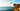 Person diving off a cliff into the ocean with a clear blue sky.