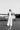 Elegant woman in a white outfit standing on an airstrip with a small airplane in the background