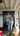 Person wearing a patterned jacket and jeans standing in a room with wooden floors and a dark wooden wardrobe.