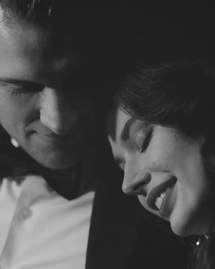 Black and white close-up portrait of a smiling woman with her eyes closed, leaning against a man in a white shirt.