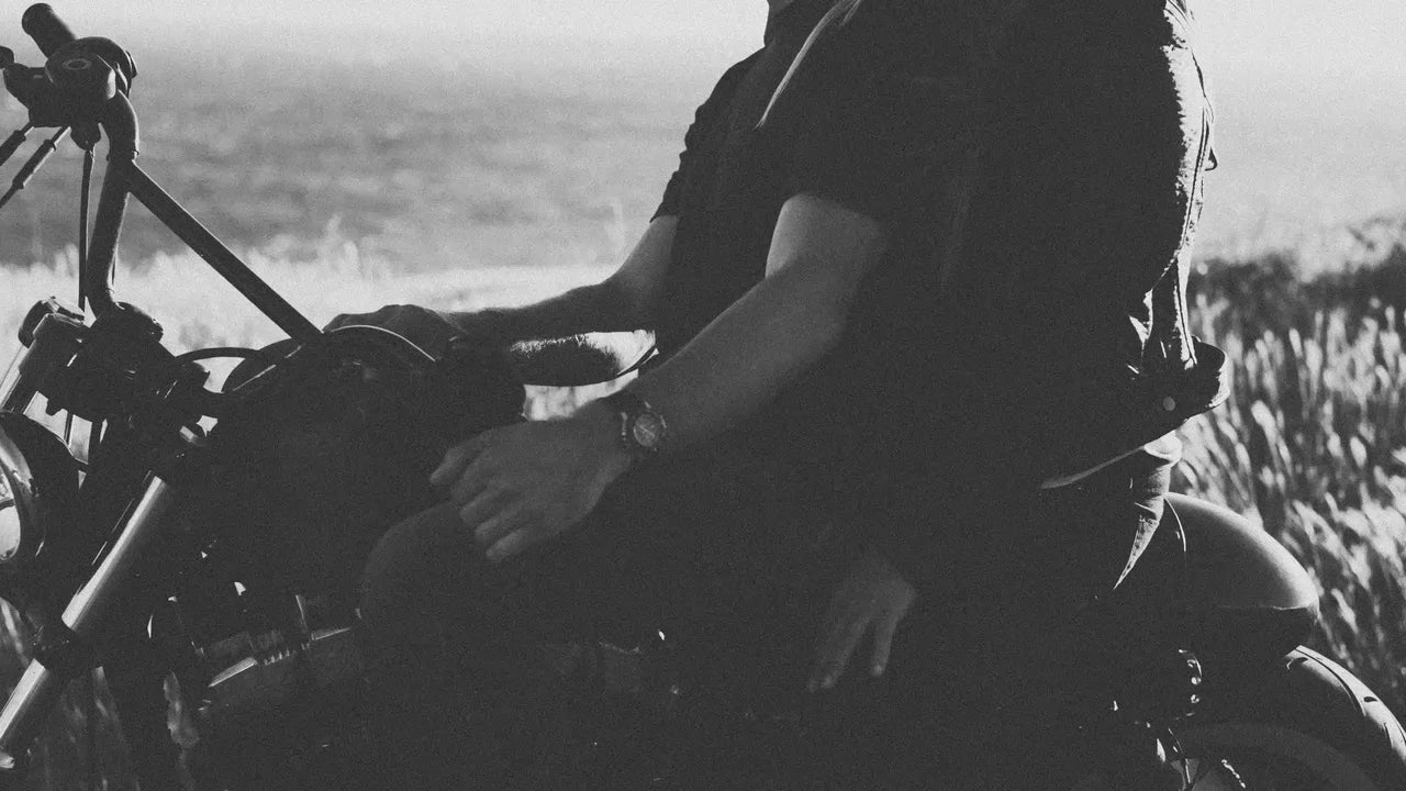 Black and white photo of a man and woman riding a motorcycle together.