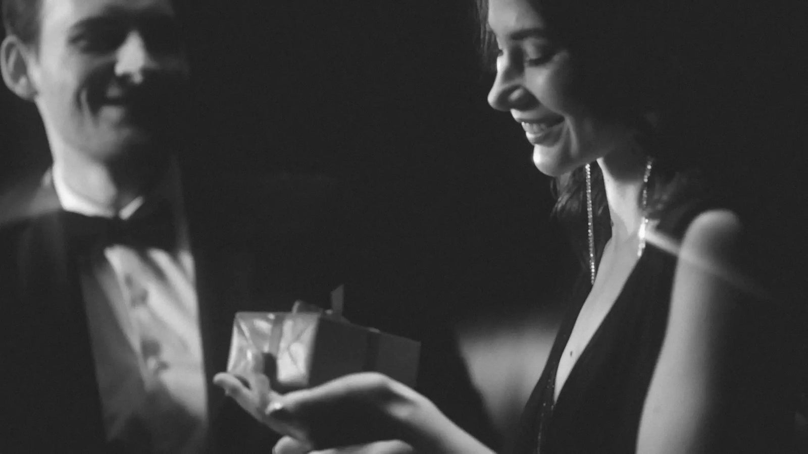 Man and woman in formal attire with a gift box, black and white photo date night