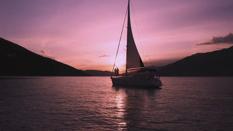 Sailboat on a lake at sunset with purple and pink sky adore